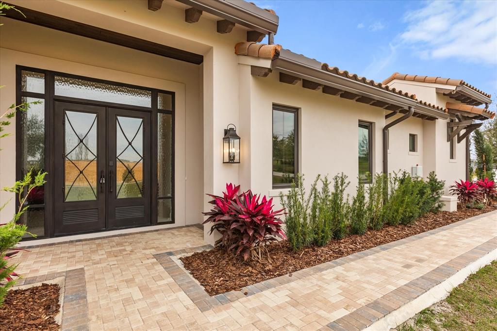 The exterior of a stucco home features a double front door and a paved walkway — 16001 VOLTERRA POINT, BELLA COLLINA, FL