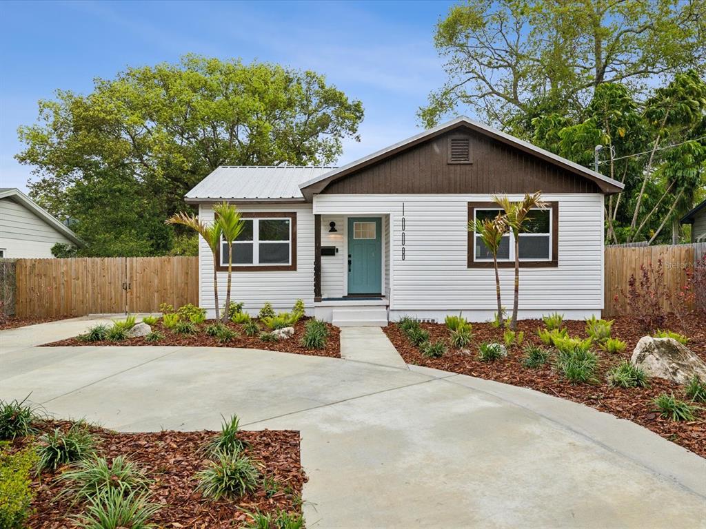 A single-story house with white siding, a metal roof, and a teal front door — 1008 E NORFOLK STREET, TAMPA, FL