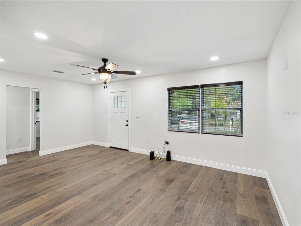 An empty room features wood-look flooring, a ceiling fan, a white door, and a window — 1008 E NORFOLK STREET, TAMPA, FL