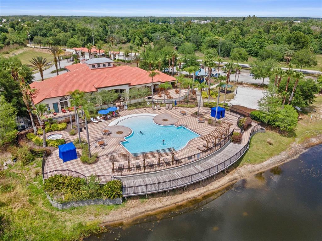 An aerial view shows a community clubhouse with a swimming pool, patio, and wooden deck — 609 FORTUNA DRIVE, DAVENPORT, FL