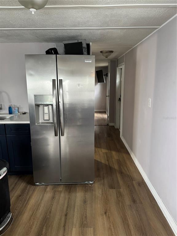 A stainless steel refrigerator stands in a kitchen with dark cabinets and wood-look flooring — 9204 66TH STREET NORTH, PINELLAS PARK, FL