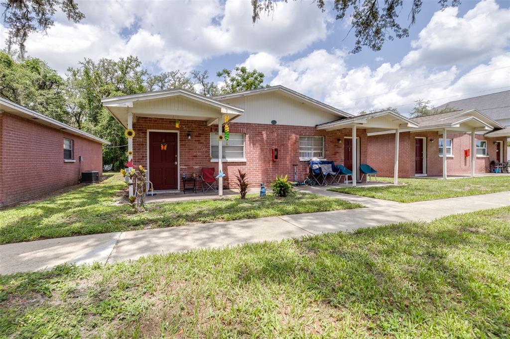 A row of single-story brick residential units with covered porches and a concrete walkway — 5901 GIBSON AVENUE, TAMPA, FL
