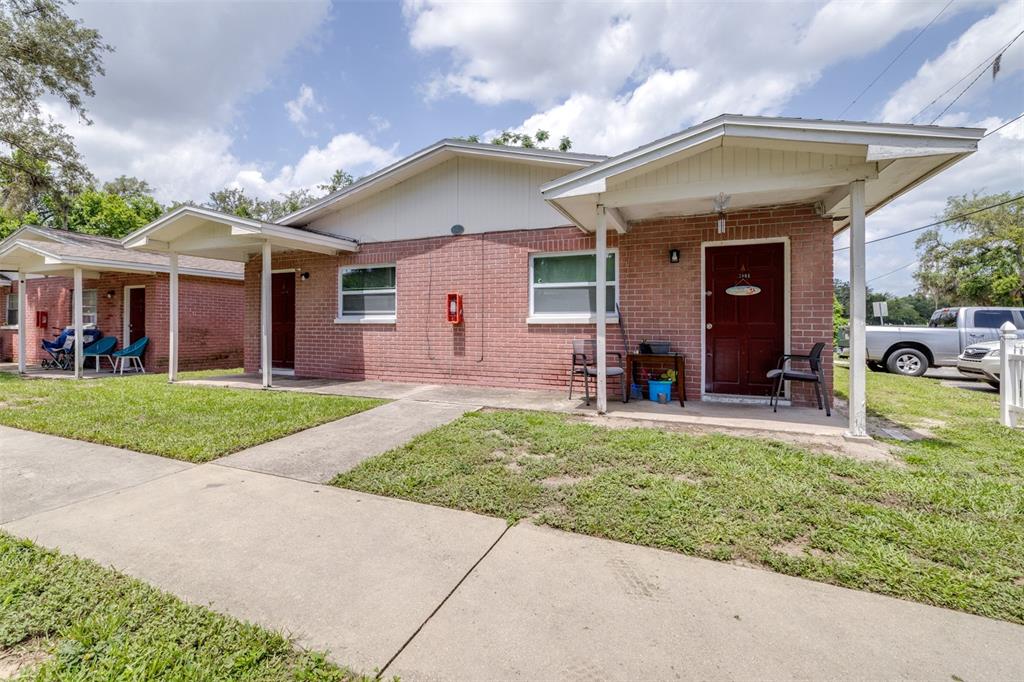 A single-story brick duplex with covered porches and concrete walkways under a blue sky — 5901 GIBSON AVENUE, TAMPA, FL