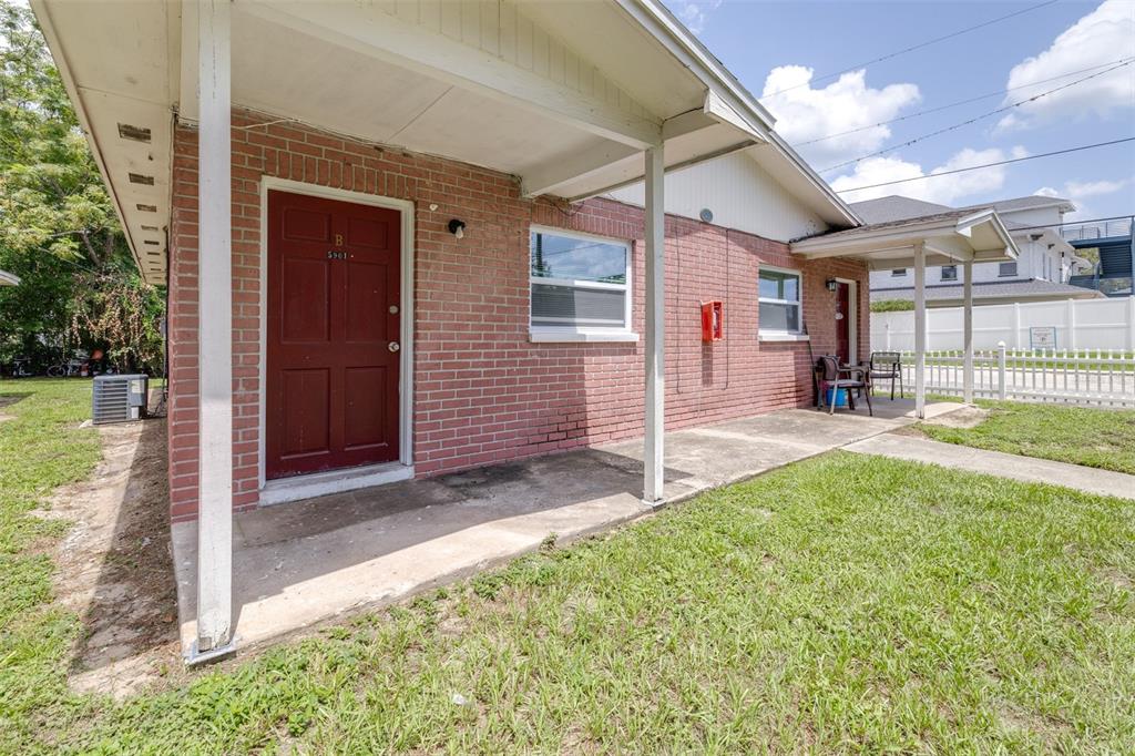 A red brick exterior building features two covered porches with white support posts and doors — 5901 GIBSON AVENUE, TAMPA, FL