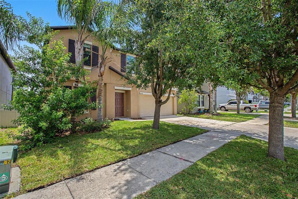 A two-story tan stucco house with a two-car garage and a front lawn — 10138 ROSE PETAL PLACE, RIVERVIEW, FL
