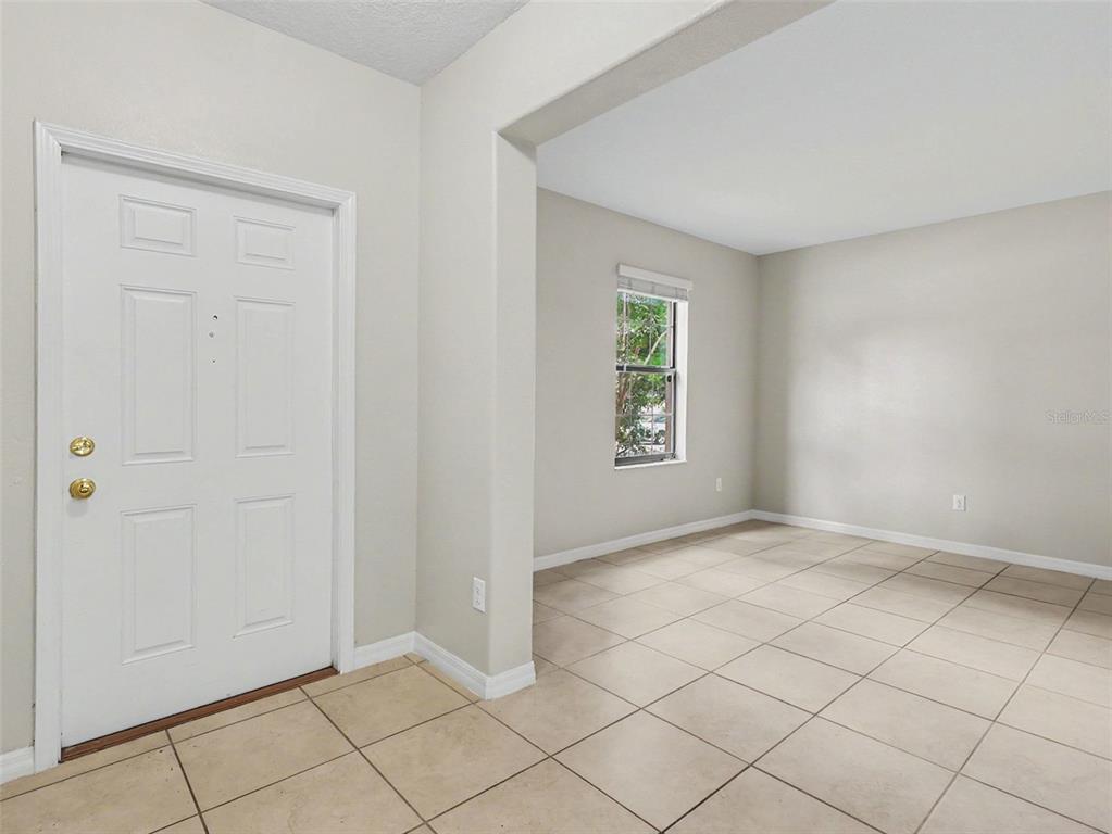 An entryway leads into a living area with beige tile flooring and neutral walls — 10138 ROSE PETAL PLACE, RIVERVIEW, FL