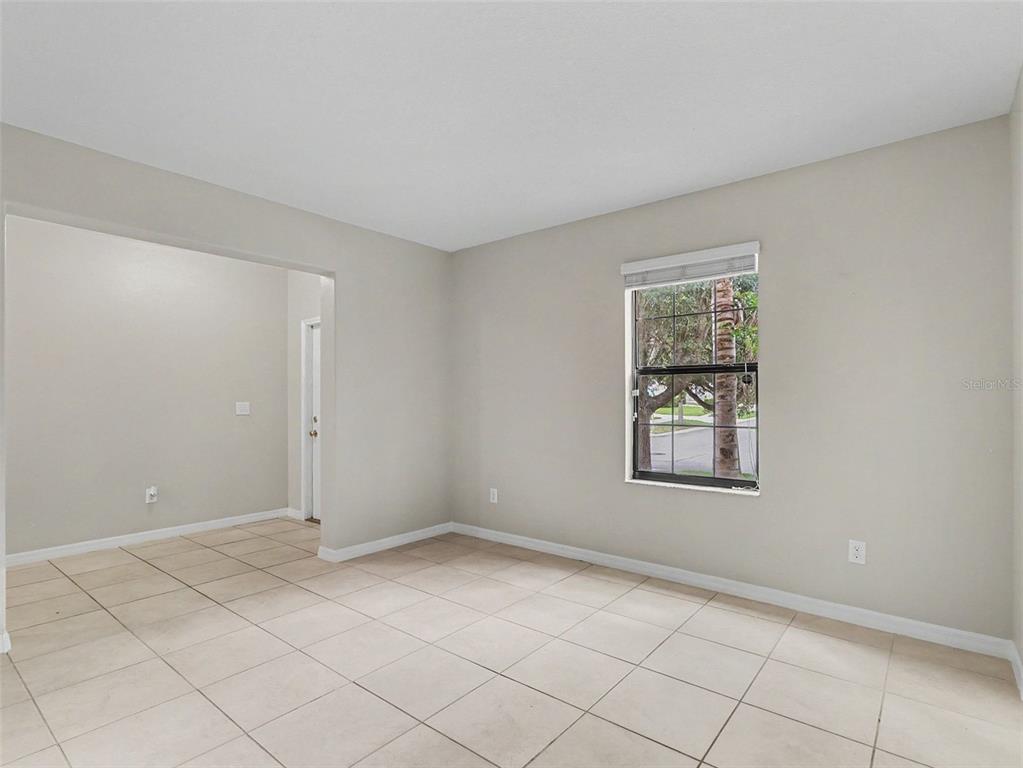 An empty room with light-colored tile flooring, beige walls, and a single window — 10138 ROSE PETAL PLACE, RIVERVIEW, FL