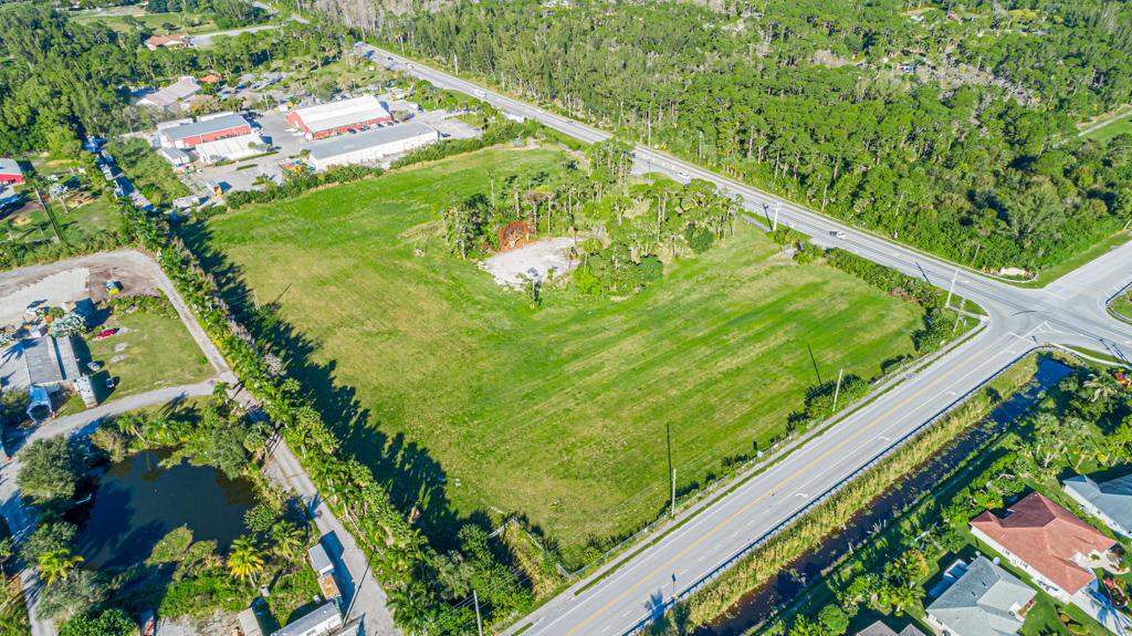 An aerial view shows a large, grassy vacant lot bordered by roads and wooded areas — 12900 Okeechobee Boulevard, FL 33470, FL