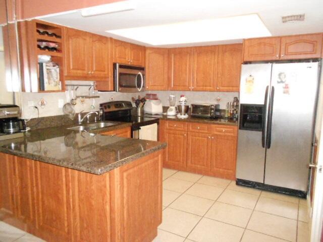 A kitchen features wood cabinets, granite countertops, stainless steel appliances, and tile flooring — 54 Matador Lane, Davie FL 33324, DAVIE, FL