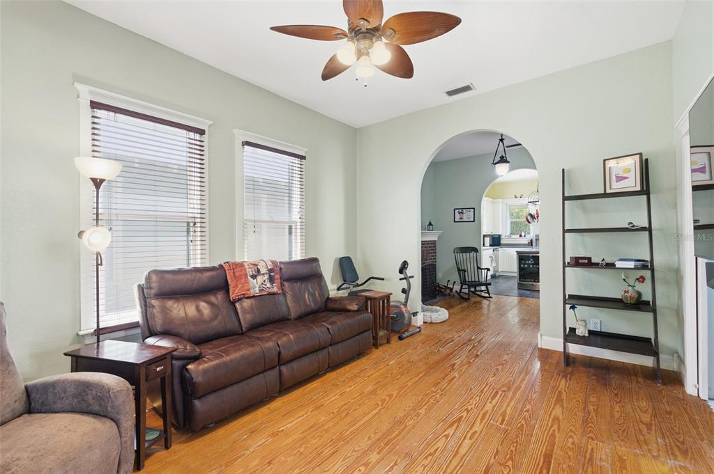 A living room with hardwood floors, a brown leather sofa, and an arched entryway — 316 E FRANCES AVENUE, TAMPA, FL