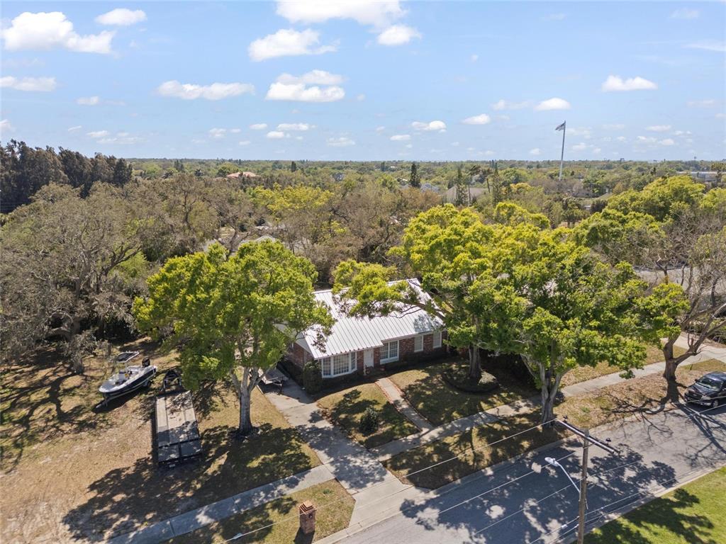 An aerial view shows a single-story brick house with a metal roof and large trees — 502 HILLCREST AVENUE, TARPON SPRINGS, FL