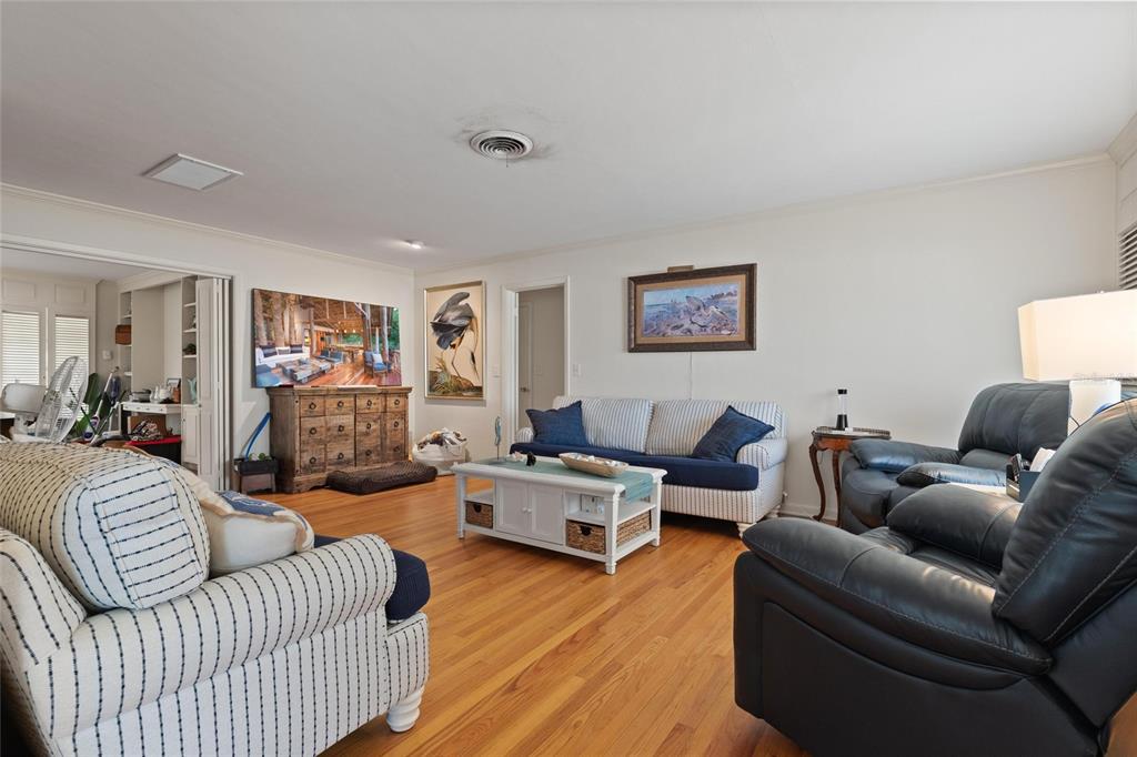 A living room features hardwood floors, striped sofas, a dark leather recliner, and wall art — 502 HILLCREST AVENUE, TARPON SPRINGS, FL