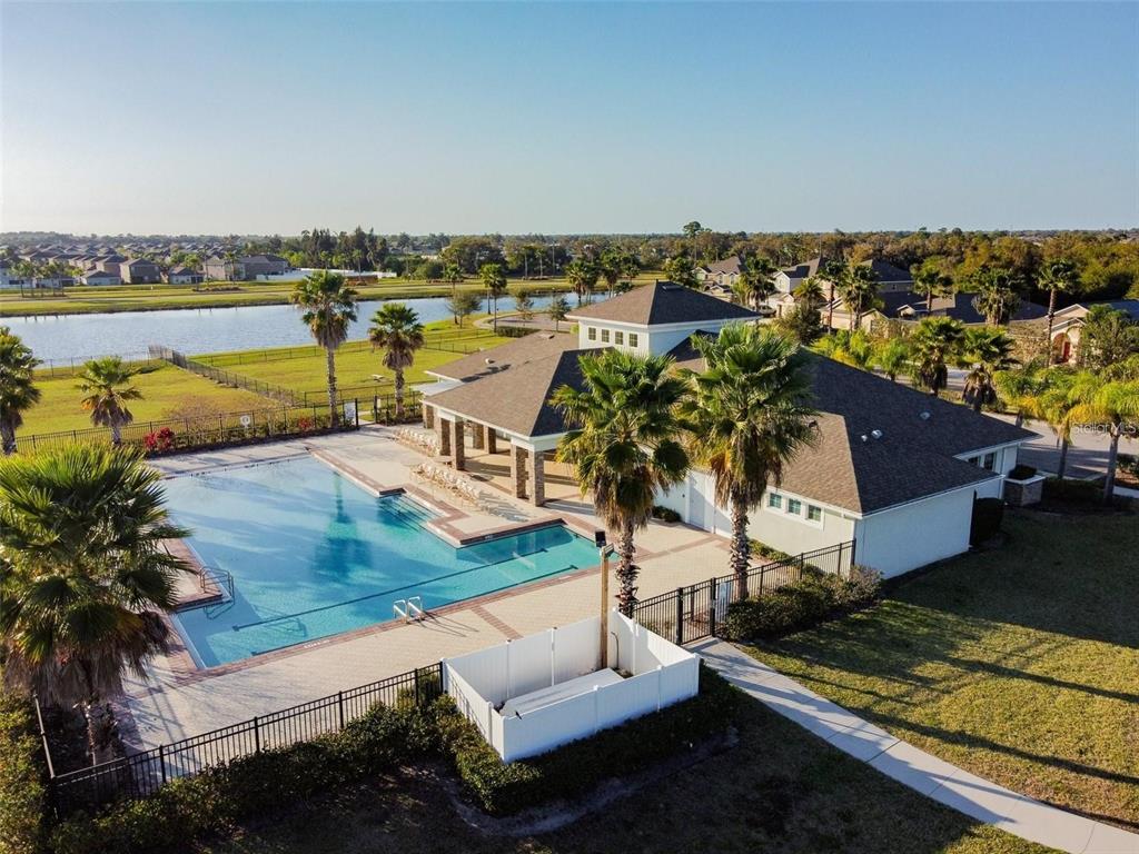 An aerial view of a community clubhouse featuring a swimming pool and surrounding palm trees — 909 MEADOW GLADE DRIVE, RUSKIN, FL