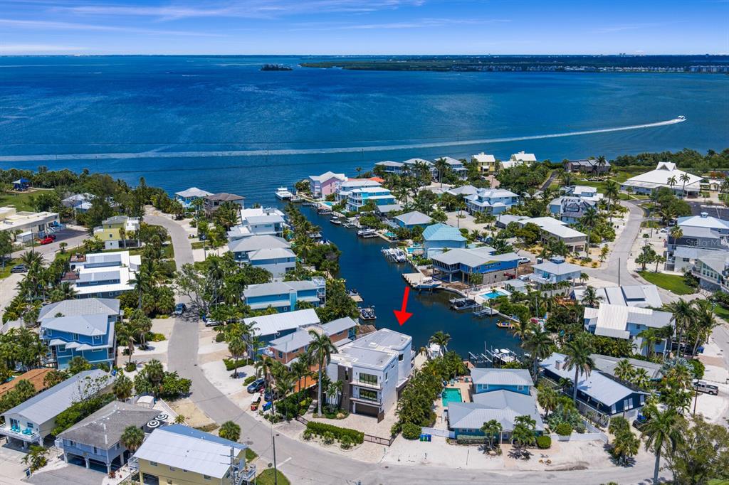 An aerial view shows a multi-story house with a flat roof situated on a canal — 201 N HARBOR DRIVE, HOLMES BEACH, FL