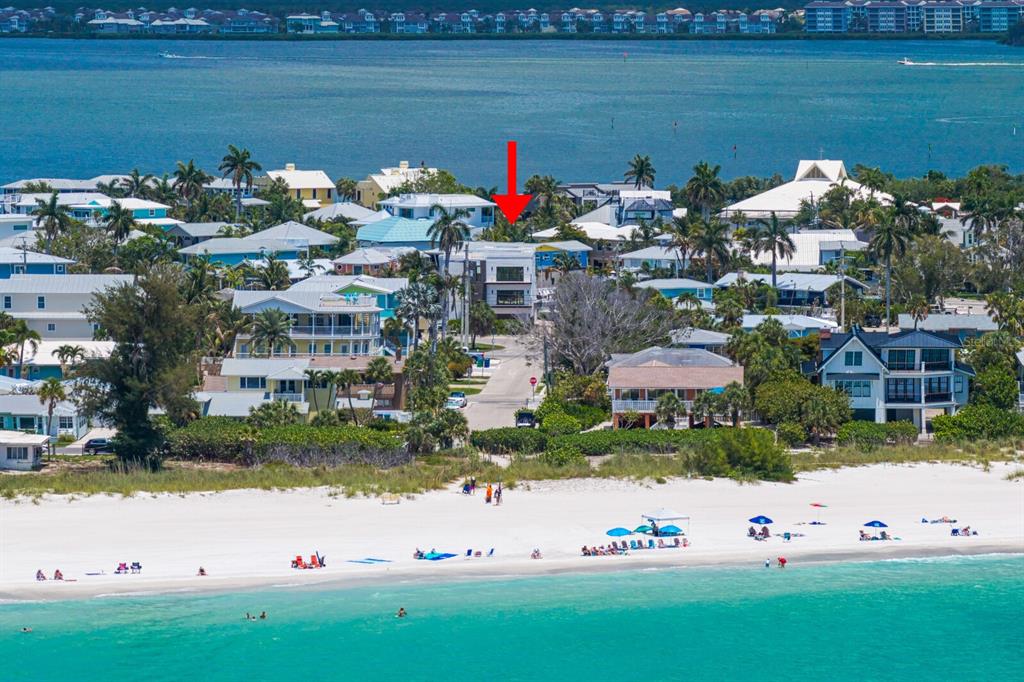 An aerial view shows a coastal neighborhood with houses near a white sand beach — 201 N HARBOR DRIVE, HOLMES BEACH, FL