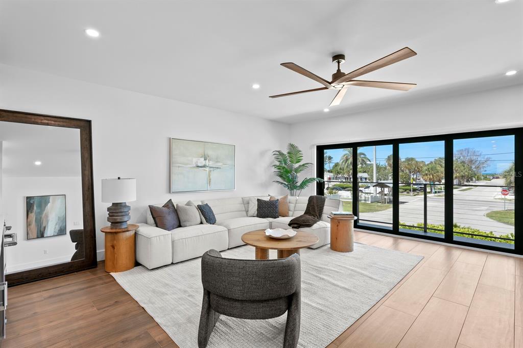 A modern living room features a white sectional sofa, wood coffee table, and large glass doors — 201 N HARBOR DRIVE, HOLMES BEACH, FL