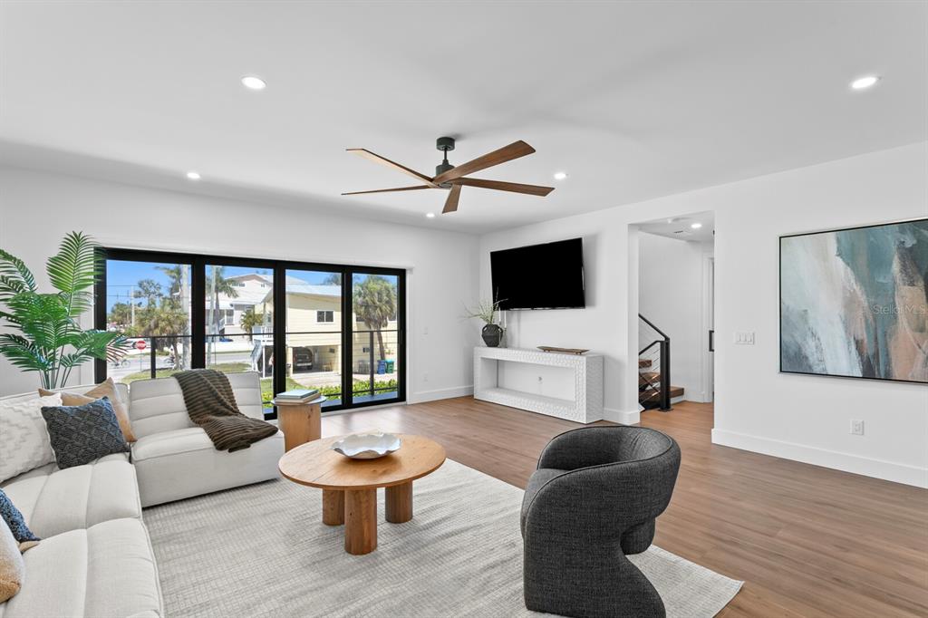 A modern living room features a white sectional, a round wooden coffee table, and sliding doors — 201 N HARBOR DRIVE, HOLMES BEACH, FL