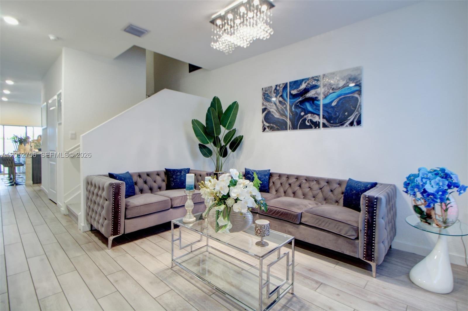 A living room features two gray tufted sofas, a glass coffee table, and blue artwork — 789 SE 16th Ct, Homestead FL 33034, HOMESTEAD, FL