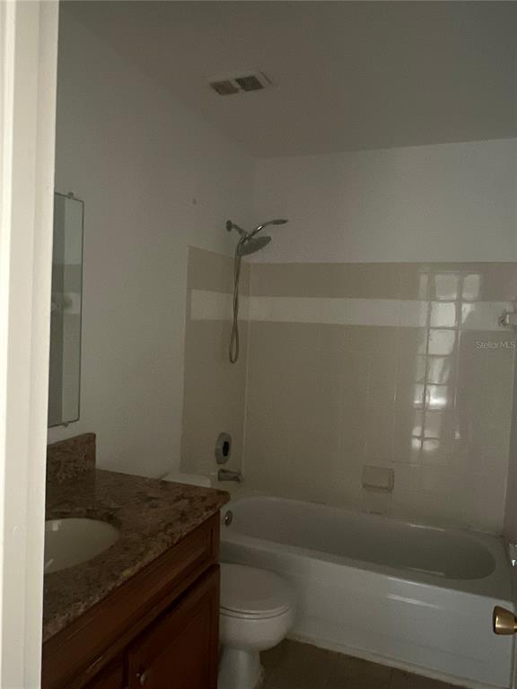A bathroom features a vanity with a stone countertop, a toilet, and a shower-tub combo — 3016 PARKWAY BOULEVARD UNIT 209, KISSIMMEE, FL