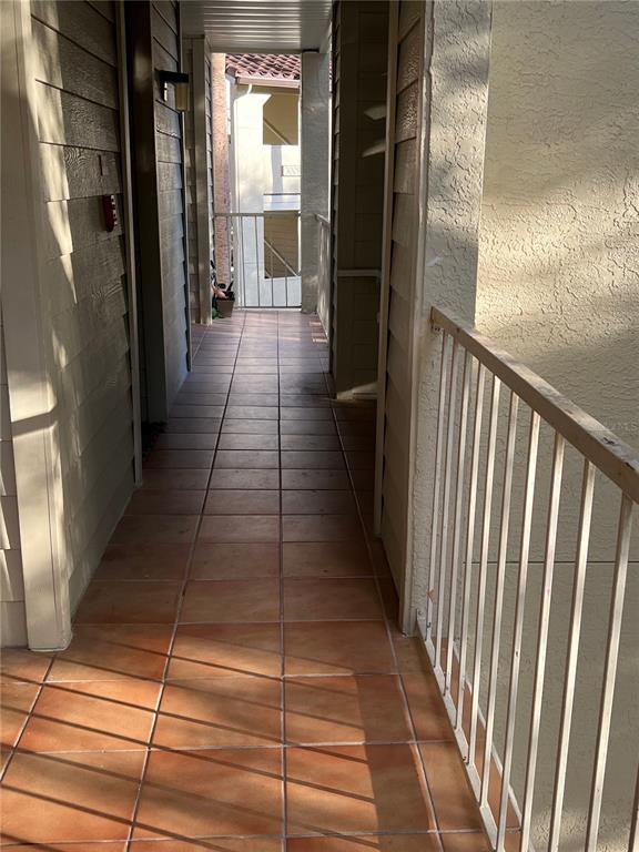An outdoor tiled walkway leads to a balcony with a white metal railing — 3016 PARKWAY BOULEVARD UNIT 209, KISSIMMEE, FL