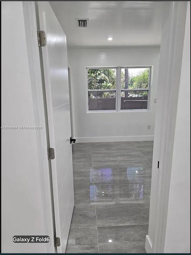 A view through a doorway into a room with gray tile flooring and windows — 13240 NE 4 Ave # 1, North Miami FL 33161, NORTH MIAMI, FL