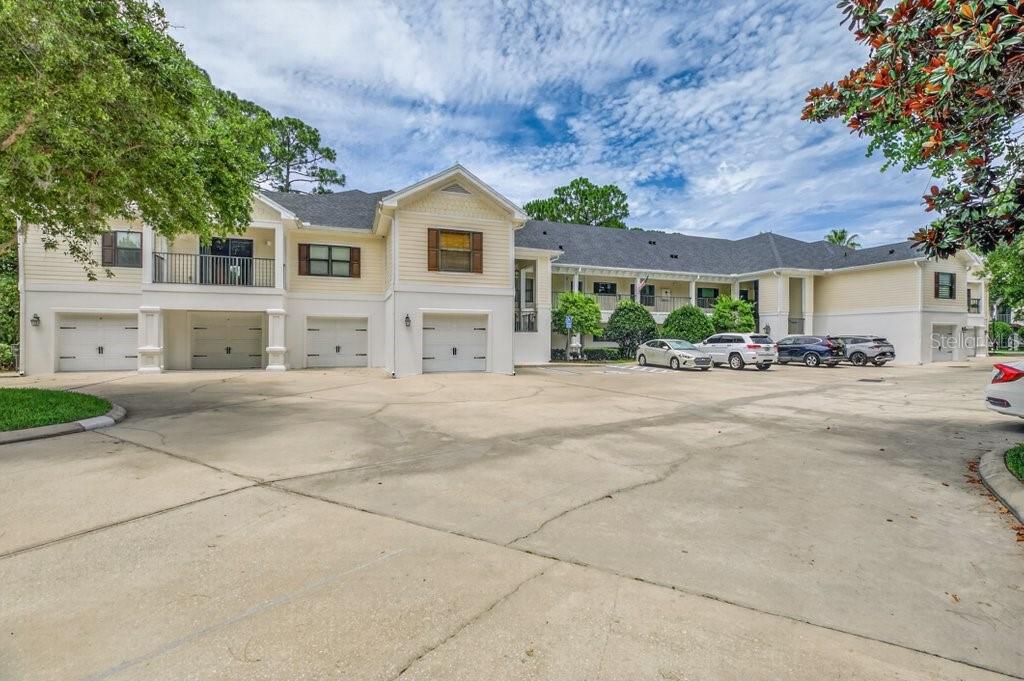 A multi-story apartment building with a large concrete parking lot and several garages — 112 LAUREL WOOD WAY UNIT 205, ST AUGUSTINE, FL