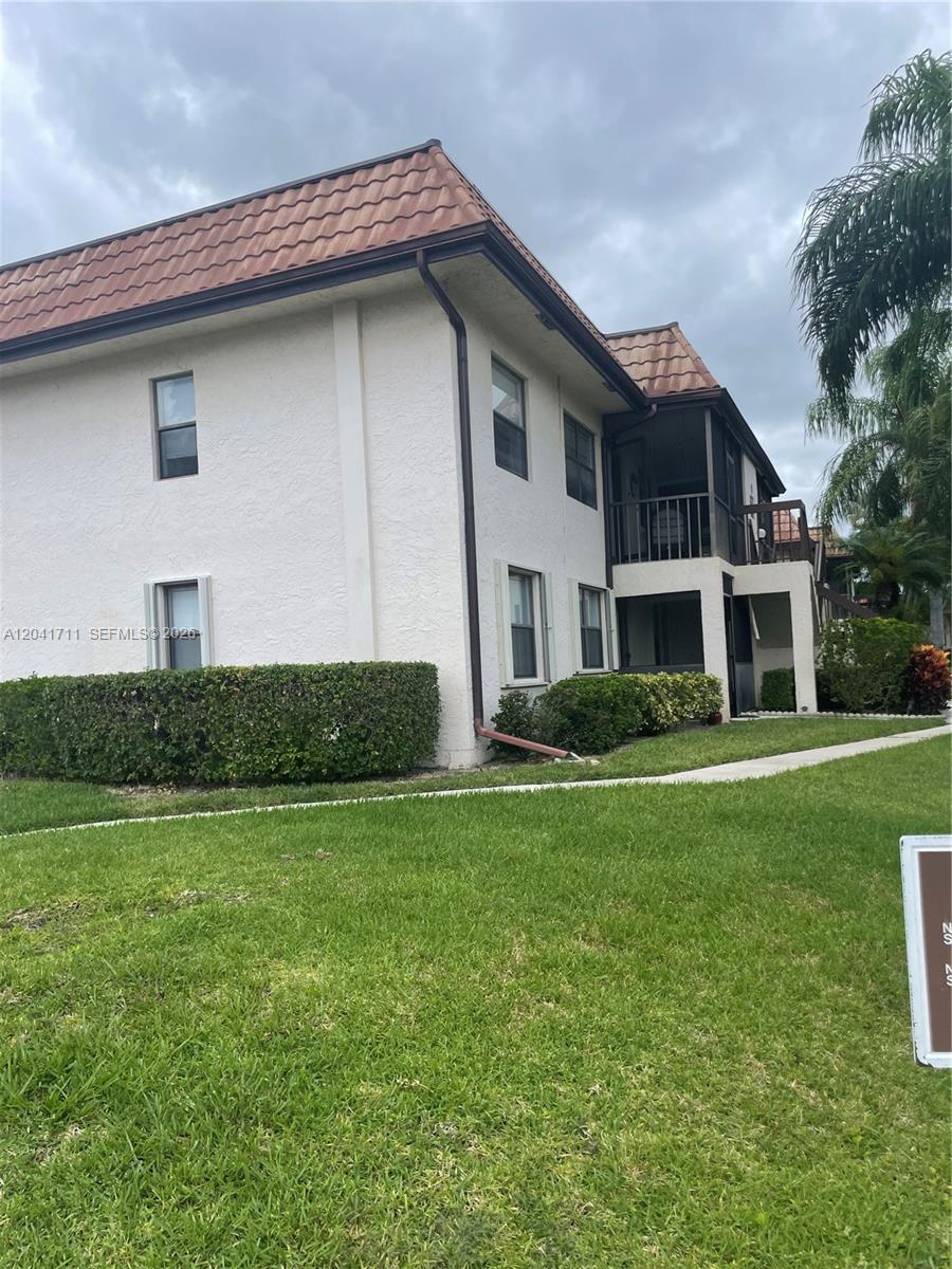 A two-story building with a tiled roof, stucco exterior, and a screened-in balcony — 7250 Golf Colony Ct # 102, Lake Worth FL 33467, LAKE WORTH, FL