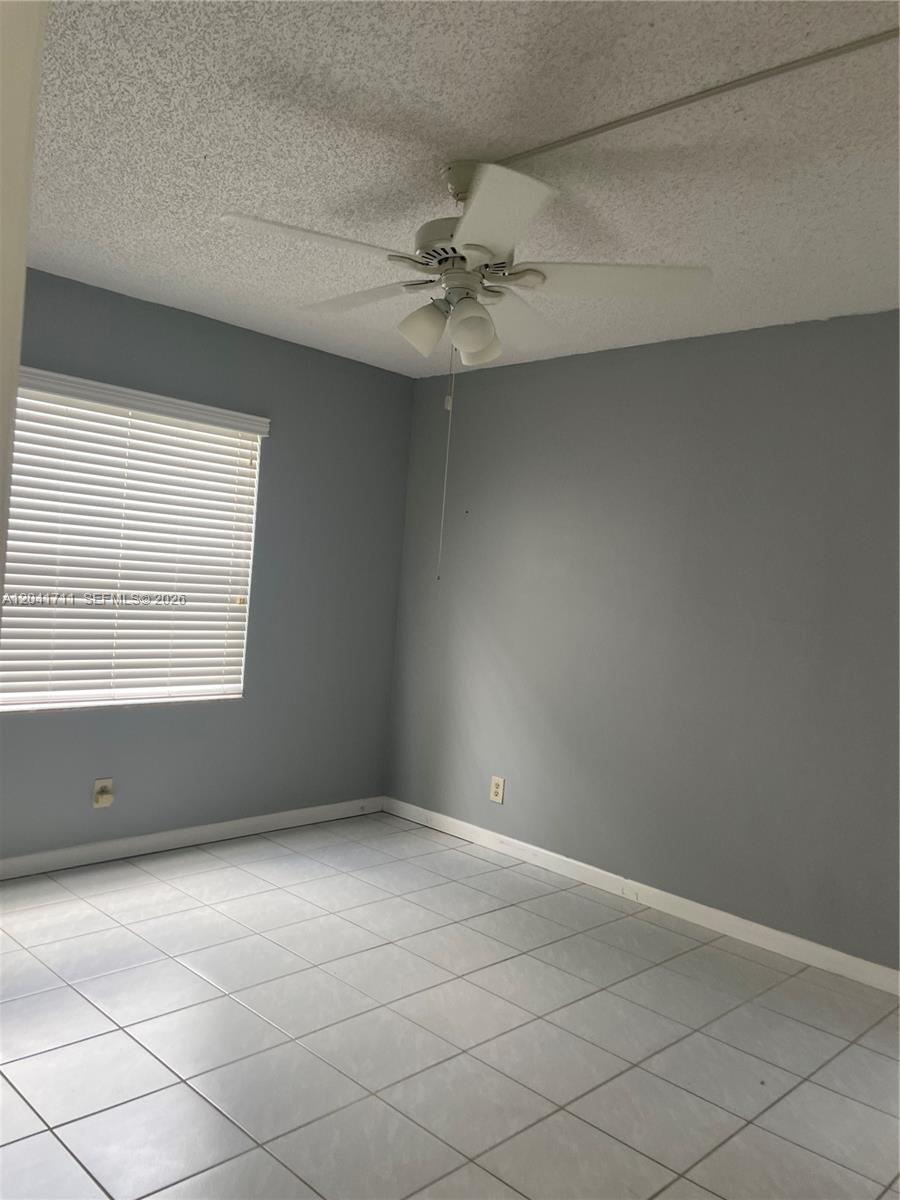 A bedroom with gray walls, white tile flooring, a ceiling fan, and a window with blinds — 7250 Golf Colony Ct # 102, Lake Worth FL 33467, LAKE WORTH, FL