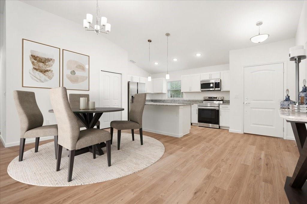 An open-concept kitchen and dining area with light wood floors, white cabinets, and stainless appliances — 37 PRINCESS RUTH LANE, PALM COAST, FL