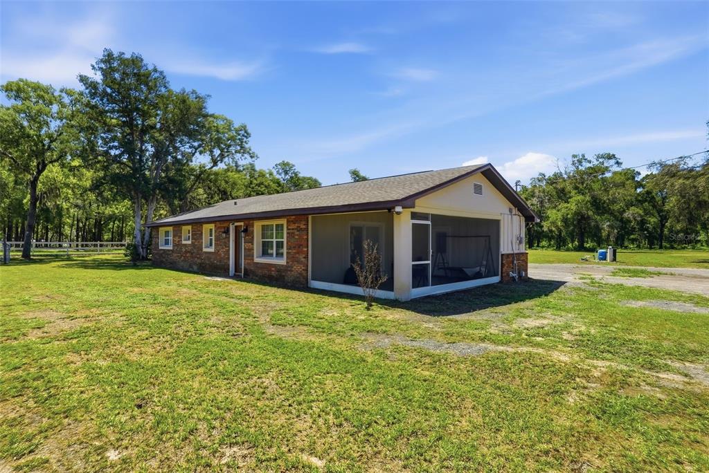 A side view of a single-story brick house with a tan chimney and grassy yard — 16700 AUBURNDALE LANE, SPRING HILL, FL