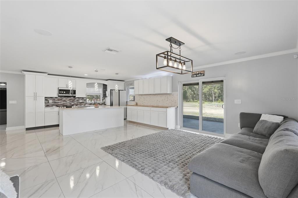 A brick house with a screened-in porch sits on a large, grassy lot with trees — 16700 AUBURNDALE LANE, SPRING HILL, FL