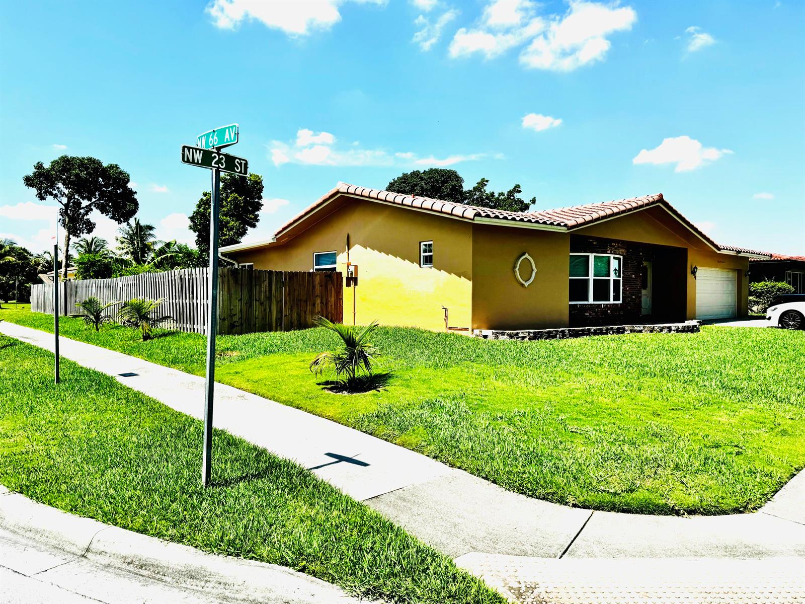 A single-story house with a yellow exterior, tile roof, and a wooden fence — 6600 NW 23rd Street, Margate FL 33063, MARGATE, FL