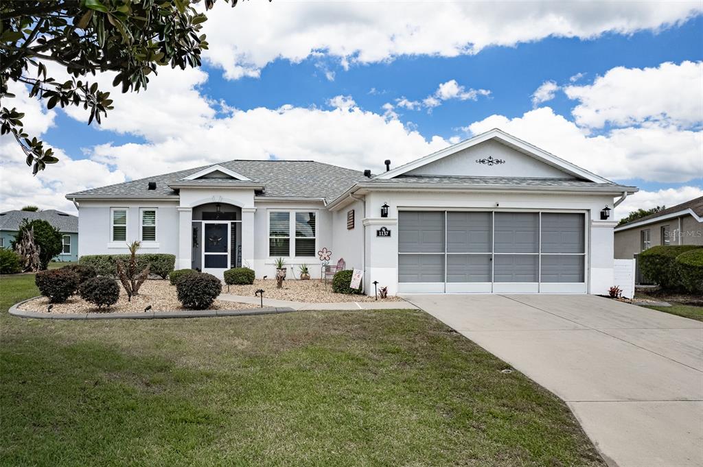 A single-story house with a white stucco exterior, gray roof, and a three-car garage — 1137 SW 156TH STREET, OCALA, FL