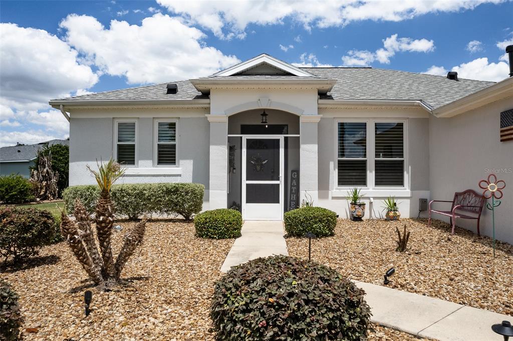 The exterior of a single-story house features a gravel yard, a walkway, and a covered entryway — 1137 SW 156TH STREET, OCALA, FL