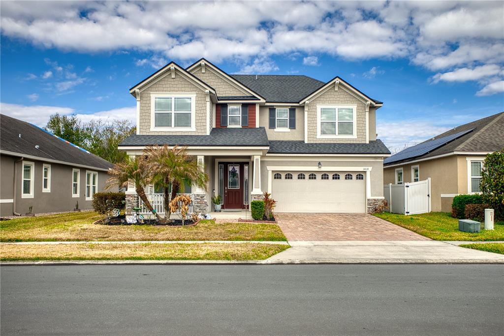 A two-story suburban house with a beige exterior, a two-car garage, and a palm tree — 3014 SERA BELLA WAY, KISSIMMEE, FL