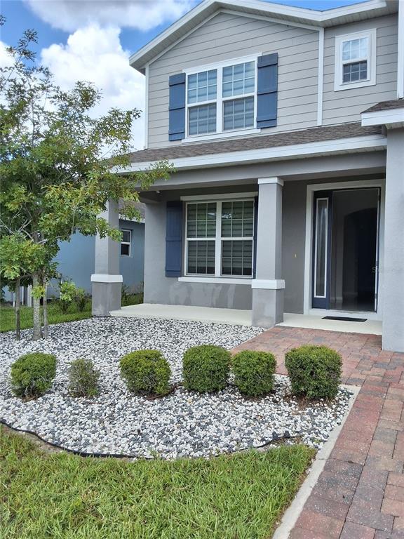A two-story house with gray siding, blue shutters, a covered porch, and a gravel yard — 4375 SILVER CREEK STREET, KISSIMMEE, FL