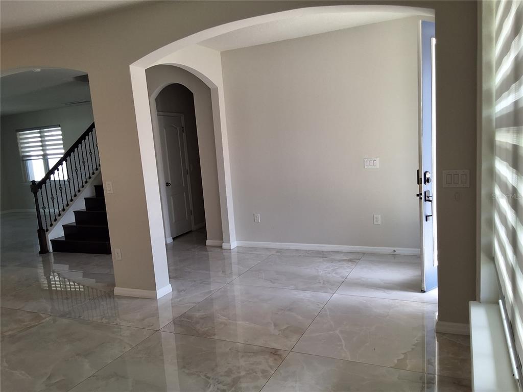 An entryway with large, polished marble-look floor tiles, arched doorways, and a staircase — 4375 SILVER CREEK STREET, KISSIMMEE, FL