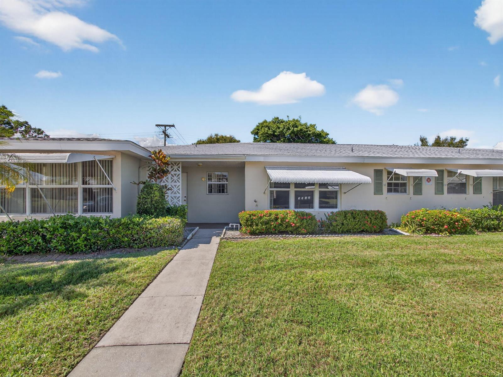 A single-story house with a concrete walkway, green lawn, and metal window awnings — 111 Lakes End Drive # B, Fort Pierce FL 34982, FORT PIERCE, FL