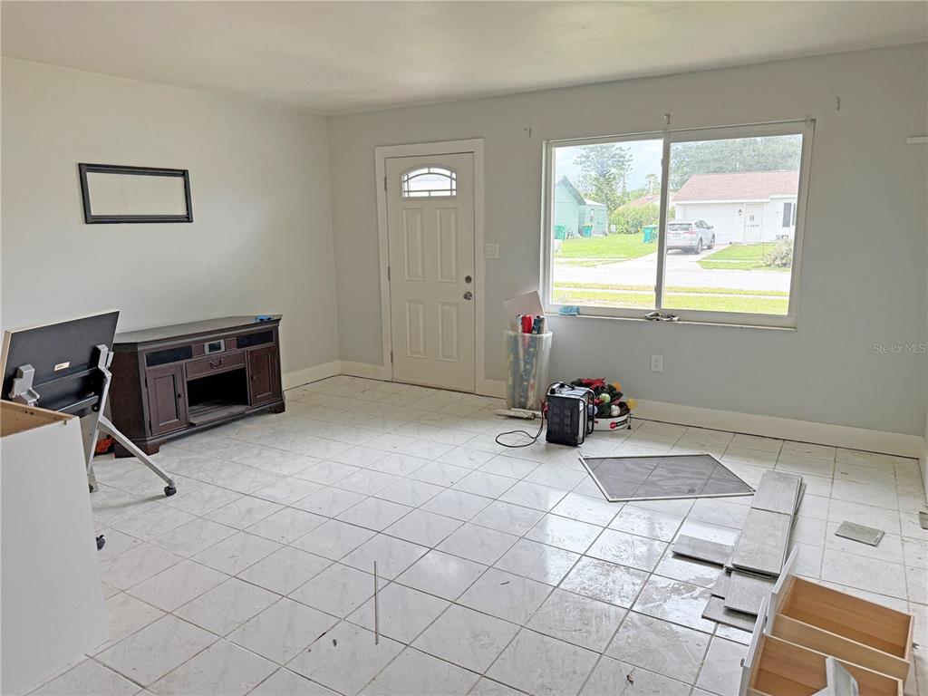 A living room with white tile flooring, a front door, and a large window — 13481 DARNELL AVENUE, PORT CHARLOTTE, FL
