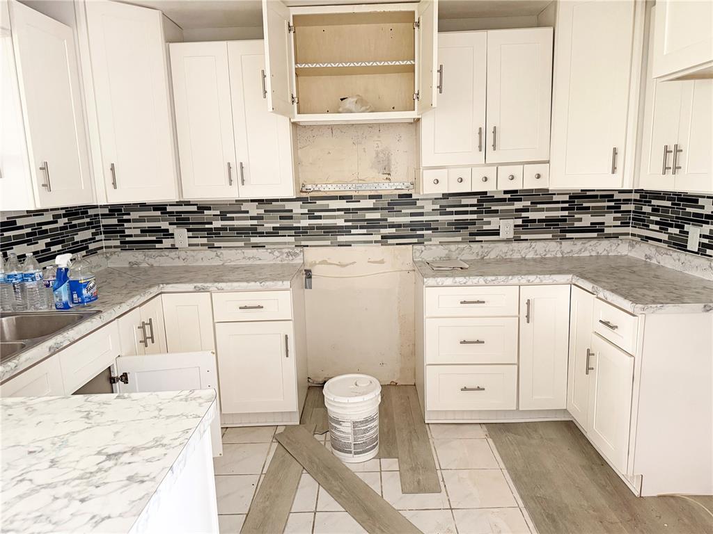 A kitchen with white cabinets, a marble-patterned countertop, and a black and white backsplash — 13481 DARNELL AVENUE, PORT CHARLOTTE, FL