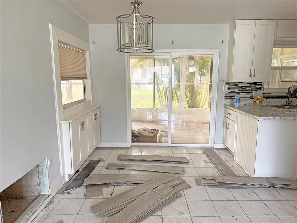 A kitchen and dining area with white cabinets, tile flooring, and unfinished floor plank installation — 13481 DARNELL AVENUE, PORT CHARLOTTE, FL