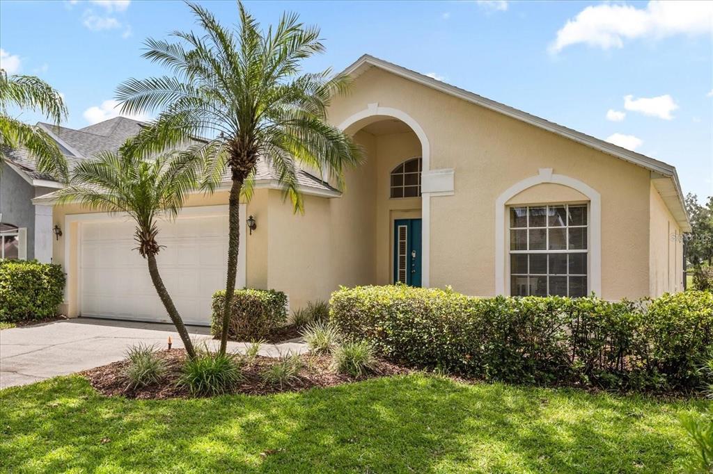 A single-story house with a beige stucco exterior, a two-car garage, and a palm tree — 2263 MALLORY CIRCLE, HAINES CITY, FL