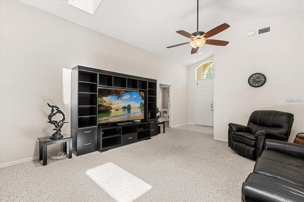 A living room features a large black entertainment center, a ceiling fan, and black leather furniture — 2263 MALLORY CIRCLE, HAINES CITY, FL