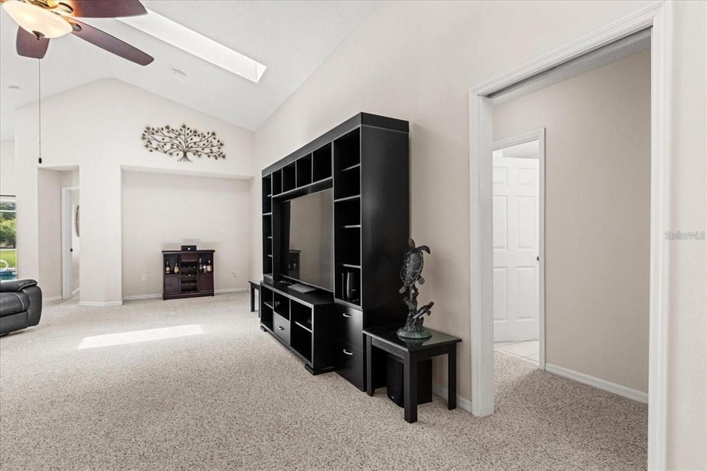A living room features a large black entertainment center, carpeted floors, and a vaulted ceiling — 2263 MALLORY CIRCLE, HAINES CITY, FL