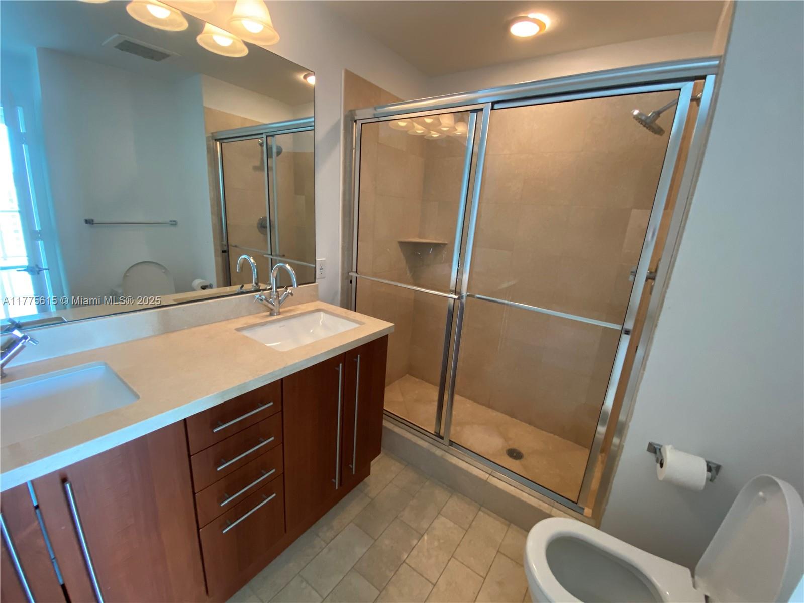 A bathroom features a double vanity with wood cabinets, a tiled shower, and a toilet — 79 SW 12 ST, Miami FL 33130, MIAMI, FL