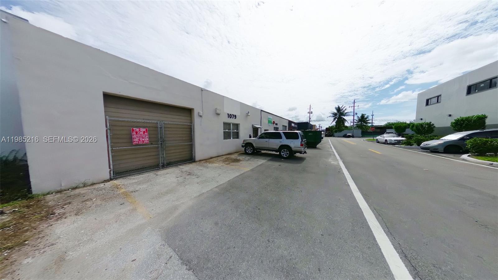 An exterior view of a commercial building with a roll-up door and parked vehicles — 1079 E 24th St # 1079, Hialeah FL 33013, HIALEAH, FL