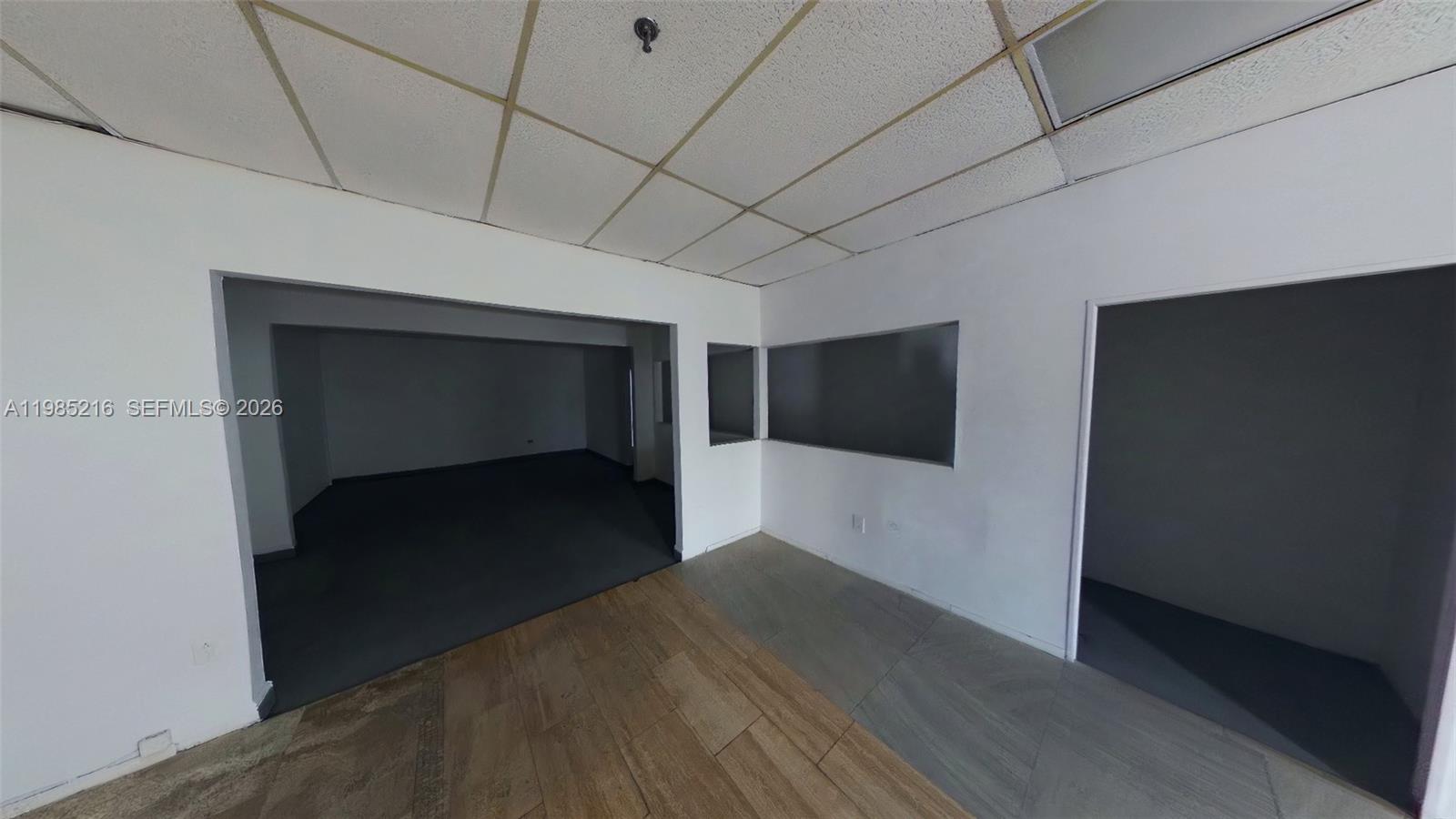 An interior view shows a room with a drop ceiling, white walls, and mixed flooring — 1079 E 24th St # 1079, Hialeah FL 33013, HIALEAH, FL