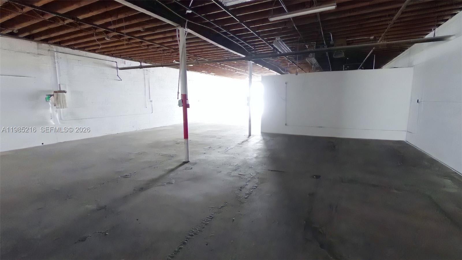 An empty industrial space features white block walls, a concrete floor, and exposed ceiling joists — 1079 E 24th St # 1079, Hialeah FL 33013, HIALEAH, FL