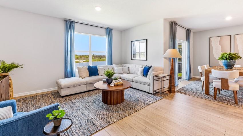 A bright living and dining area features a sectional sofa, round coffee table, and wood flooring — 2968 FISHERY COURT, LAKEWOOD RANCH, FL