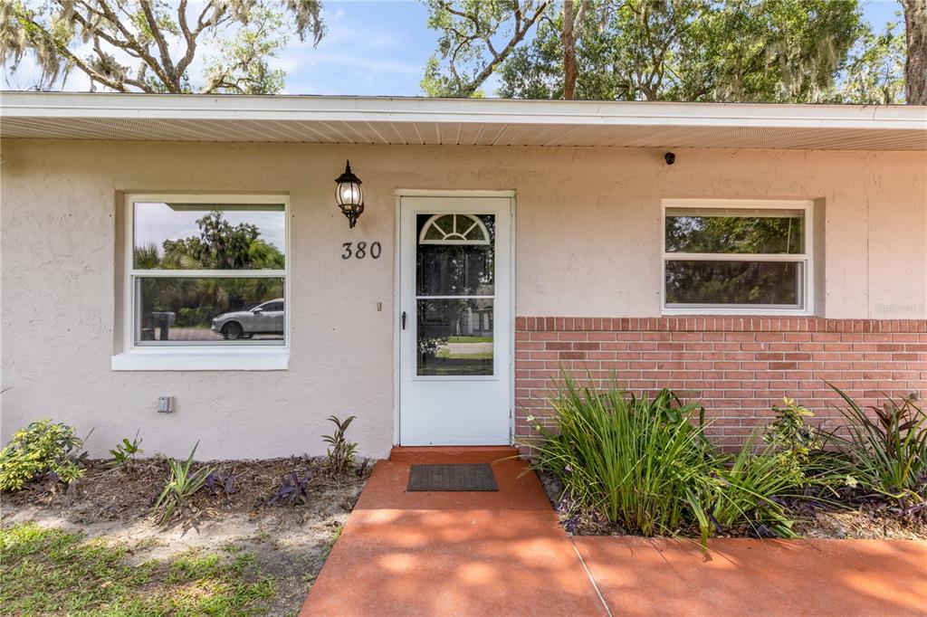 The exterior of a single-story house features a white door, brick accents, and a walkway — 380 JULIA AVENUE, ORANGE CITY, FL